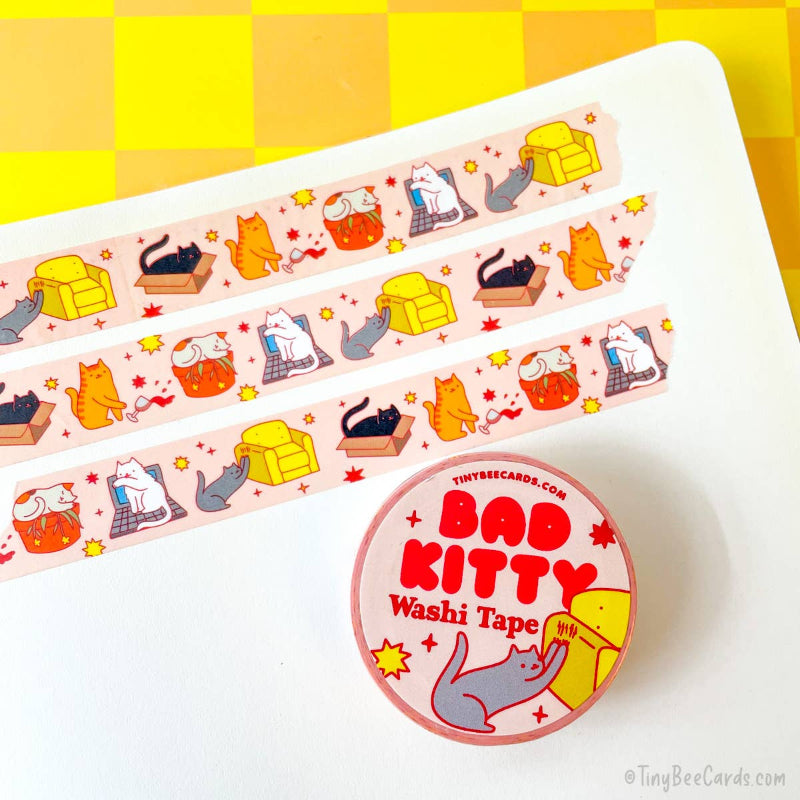Washi tape with cat designs on a white surface with a yellow checkered background