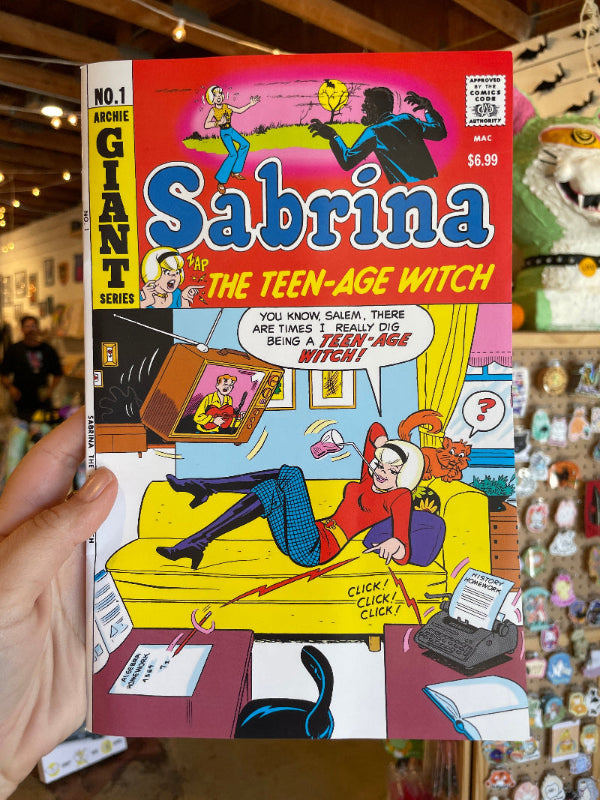 Comic book titled 'Sabrina the Teenage Witch' held in front of a store shelf.